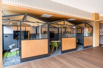 A lounge area with a table and chairs and a lobby with glass walls